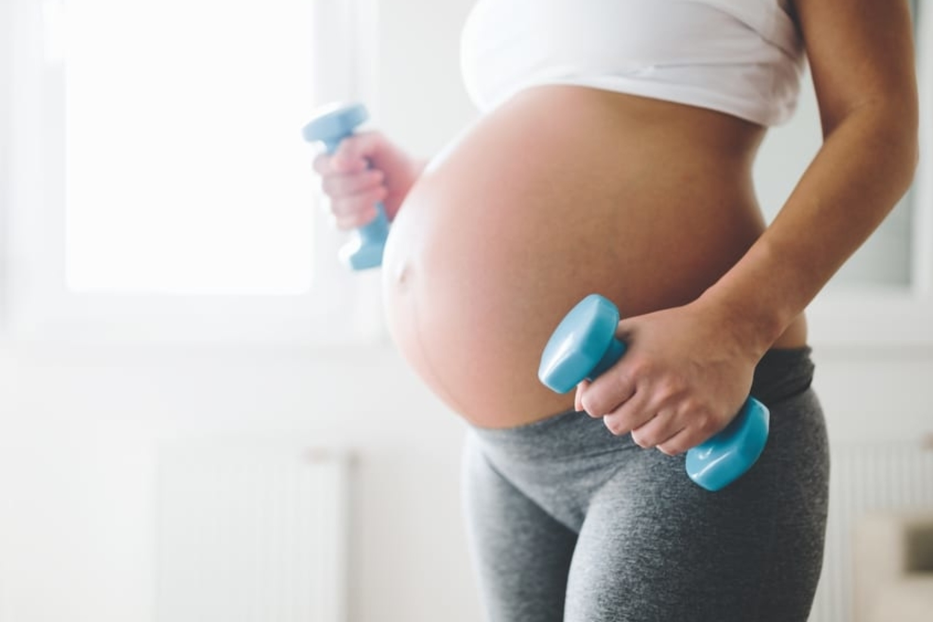 Zwangere vrouw tilt gewichten
